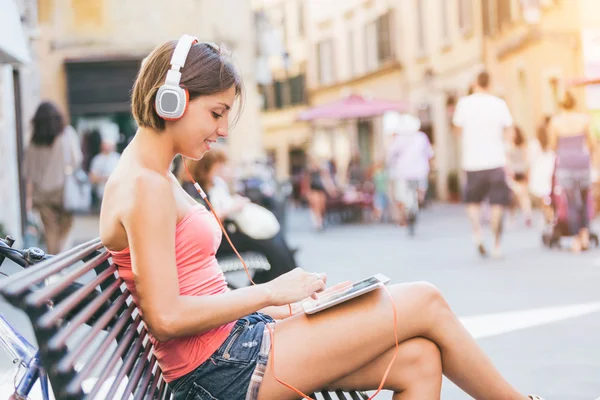 Belle fille avec écouteurs et tablette numérique dans la ville — Photo