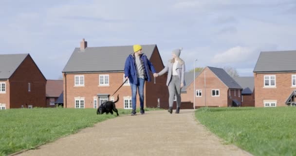 Кінематографічний справжній знімок молодої щасливої усміхненої пари, що йде з собакою — стокове відео