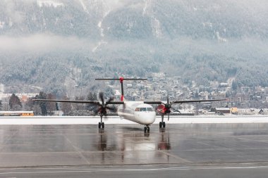 Kar arkaplanlı uçak motorları - Küçük bölgesel jet kış günü Innsbruck havaalanından kalkışa hazırlanıyor - seyahat ve ulaşım kavramları