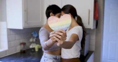 Mutlu kız arkadaşlar lezbiyen çift kucaklaşıyorlar ve ellerinde kalp şeklinde bir gökkuşağı