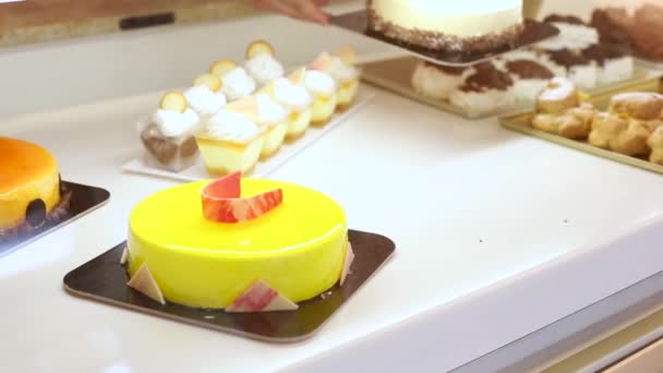 Cukiernik w pracy w cukierni przygotowuje wystawowe okno z pysznym ciastem — Wideo stockowe