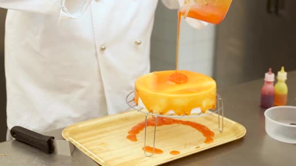 Cukiernik w pracy w cukierni ozdabiający ciasto słodkim lukrem pomarańczowym — Wideo stockowe
