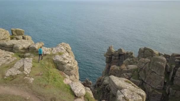 Чоловік на вершині скелі в Корнуолі з насолодою спостерігає за краєвидом. — стокове відео