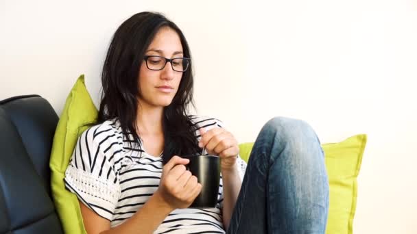 Wanita santai di sofa dan minum teh panas atau kopi — Stok Video
