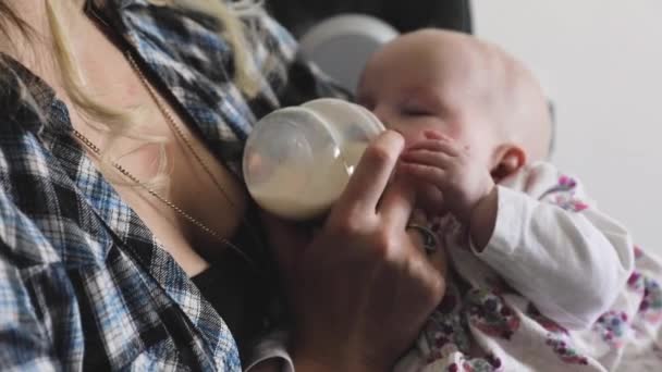 Mãe alimentando sua menina com mamadeira de leite no sofá — Vídeo de Stock