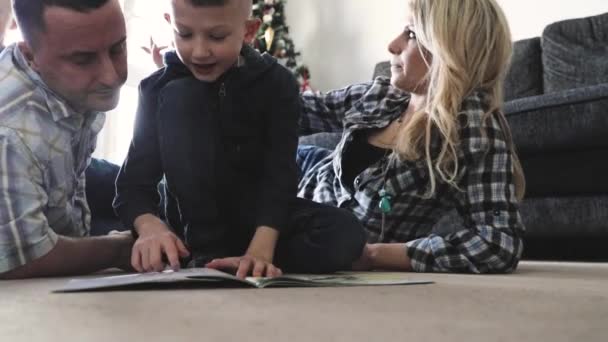 Padres ayudando a su hijo a leer un libro y hacer la tarea escolar — Vídeos de Stock