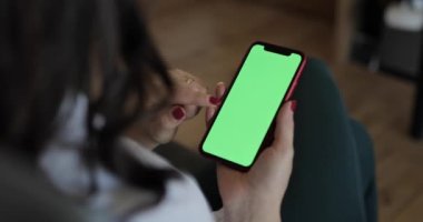 Yeşil ekranlı akıllı telefon kullanan bir kadın