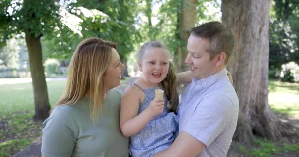 Ευτυχισμένη οικογένεια απολαμβάνει το χρόνο μαζί στο πάρκο με το κορίτσι τρώει παγωτό — Αρχείο Βίντεο
