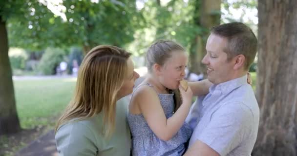 Familia feliz disfrutando de tiempo juntos en el parque con la chica comiendo helado — Vídeo de stock