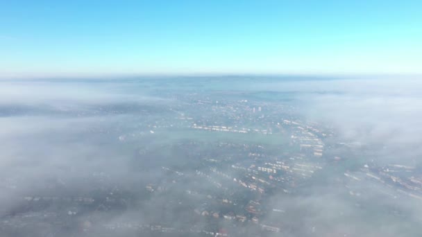 Flygfoto över en stad täckt av dimma och moln — Stockvideo