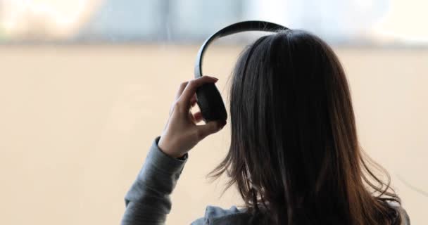 Femme aux cheveux longs portant un casque et écoutant de la musique, vue arrière — Video