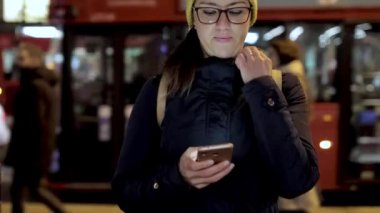 Londra 'da gece vakti akıllı telefon kullanan bir kadının otantik görüntüsü.