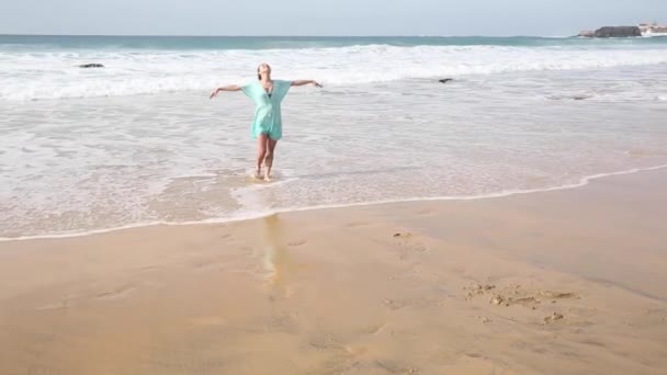 Hermosa mujer sola en la playa caminando y salpicando agua en Fuerteventura — Vídeo de stock