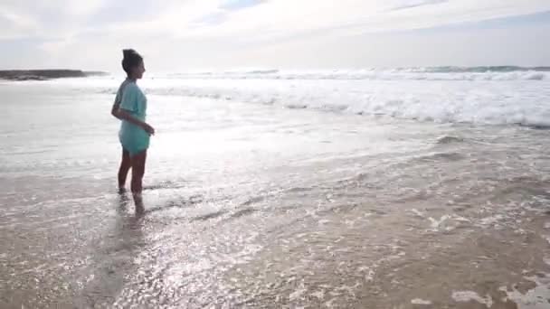 Auténtico disparo de la mujer sola en la playa frente a las olas salpicaduras — Vídeos de Stock