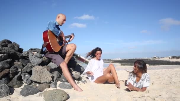 Glada vänner som spelar musik och dansar vid havet — Stockvideo