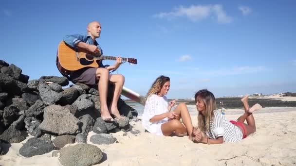 Gelukkige vrienden die muziek spelen en dansen aan zee — Stockvideo