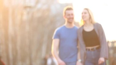 Happy young couple in love walking and smiling in London at sunset with warm flare on frame - Lifestyle and love concepts with caucasian young man and woman