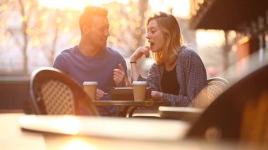 Happy young couple having a coffee together and looking at a digital tablet having fun and laughing - Lifestyle and technology concepts