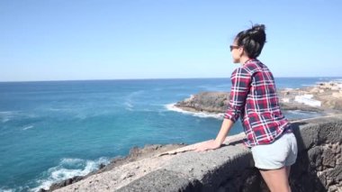 Authentic shot of a young woman at seaside enjoying the view of the ocean on a sunny day in Fuerteventura - Travel and lifestyle concepts
