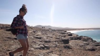 Authentic shot of a young woman at seaside enjoying the view of the ocean on a sunny day in Fuerteventura - Travel and lifestyle concepts