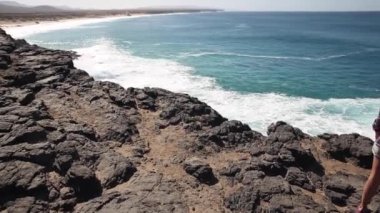Authentic shot of a young woman at seaside enjoying the view of the ocean on a sunny day in Fuerteventura - Travel and lifestyle concepts