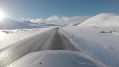 Driving in Iceland across icy countryside and snowy mountains on an empty road exploring amazing places and destinations - Travel and transportation concepts
