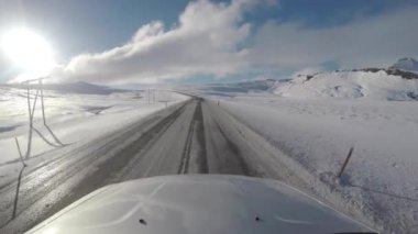 Driving in Iceland across icy countryside and snowy mountains on an empty road exploring amazing places and destinations - Travel and transportation concepts