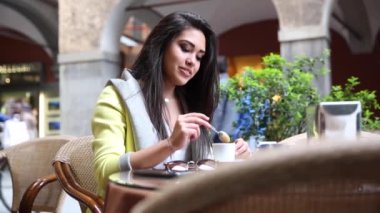 Beautiful mixed race girl asian and caucasian enjoying an espresso coffee in a cafe in Italy on a typical city sitting at the table outside