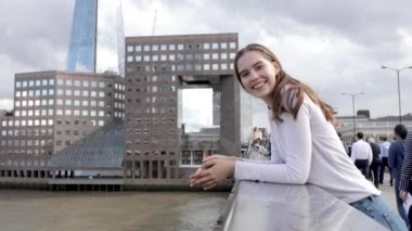 Young beautiful woman portrait in the city, slow motion shot - Smiling happy woman with London landmarks and Thames river on background - Lifestyle and relax concepts
