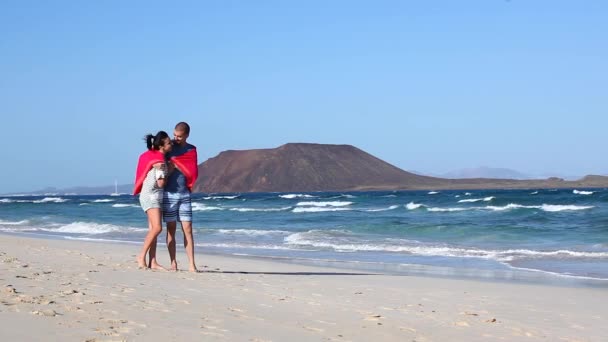 フエルテベントゥラの海辺で一緒に過ごす愛の時間の若いカップルの本格的なショットは 新婚旅行でタオルと風と遊ぶ — ストック動画
