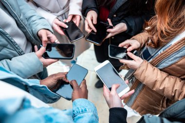 Sosyal medya ağında paylaşmak ve iletişimi koparmamak için cep telefonlarına bağımlı bir grup çok ırklı arkadaş akıllı telefon, arkadaşlık ve teknoloji kavramlarına yakın durun.