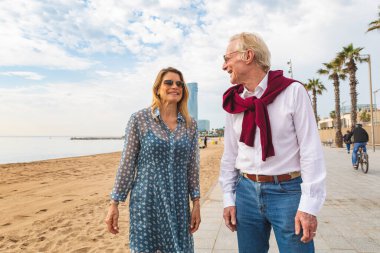 Barcelona 'da deniz kenarında yürüyen otantik mutlu çift - Barselona' da bir yaz gününde yetişkin kadın ve erkek kaynaşıyor ve birlikte vakit geçiriyorlar - Barcelona sahillerinde yaz ve seyahat kavramları