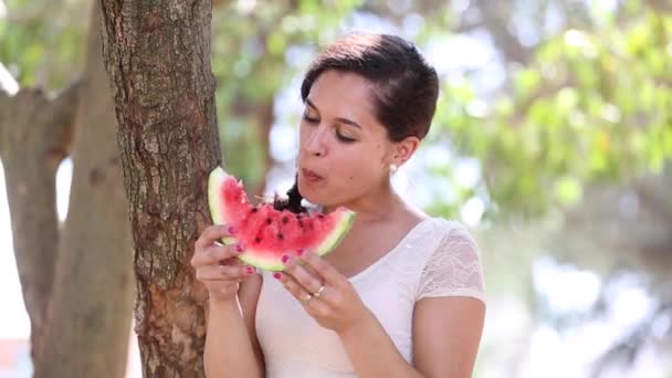 Mooie jonge vrouw eten een stuk van watermeloen en glimlachen — Stockvideo