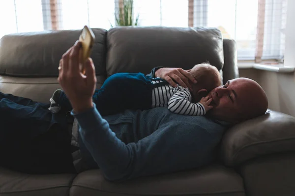 Autentický Snímek Muže Ležícího Pohovce Svým Synem Používajícího Smartphone Otec — Stock fotografie
