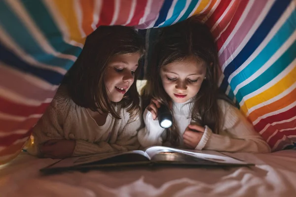 Two Happy Girls Reading Book Bed Duvet Using Torch Light — Stock Photo, Image