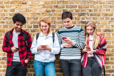 Londra 'da cep telefonu kullanan ve arayan bir grup genç öğrenci - sosyal medya ve internet bağımlısı en iyi arkadaşlar - Londra' da yaşam tarzı ve arkadaşlık