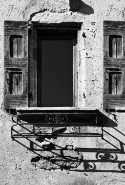 Siyah beyaz çürüyen ahşap panjurları olan çok eski bir Fransız evinin cephesi.