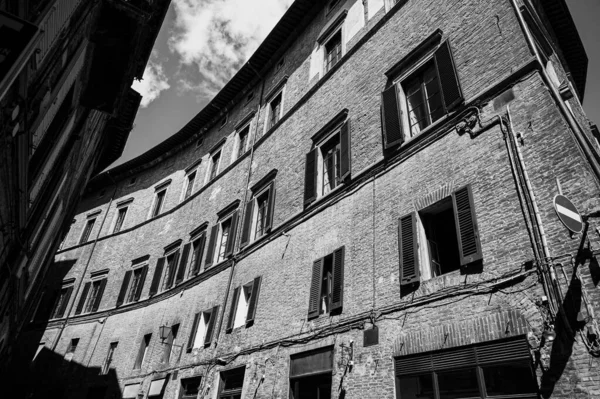 The architecture of the medieval Italian city Siena, old facade, windows with shutters and the spirit of antiquity in black and white