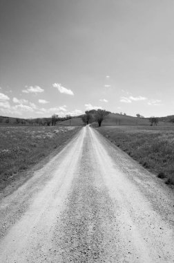 Tuscany bahar tarlaları arasında siyah beyaz toprak yol