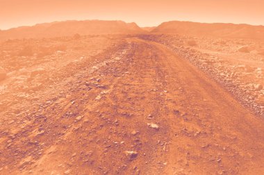 Kanyona giden toprak yol, İsrail 'in güneyindeki kayalık çölde şafak vakti modern tarzda oyulmuş..