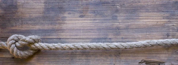 Tavola di legno con una consistenza ruvida e una corda — Foto Stock