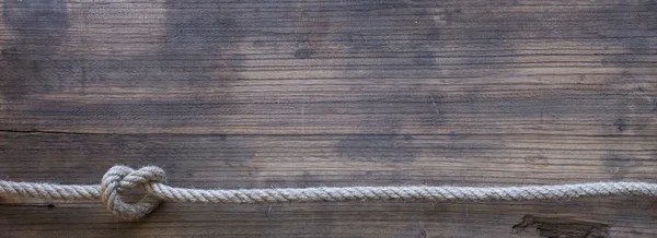 Tablero de madera con una textura áspera y una cuerda — Foto de Stock