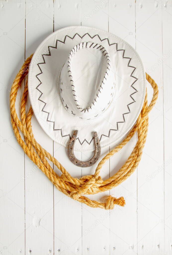 Classic white cowboy hat lasso and horseshoe wild west still life on rough white wooden table