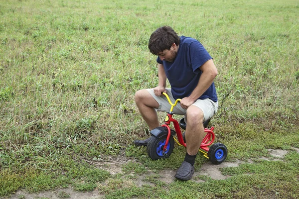 Взрослый мужчина на маленьком трехколесном велосипеде — стоковое фото