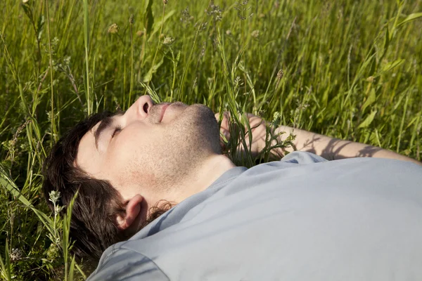 Junger Mann schläft auf einer Wiese — Stockfoto