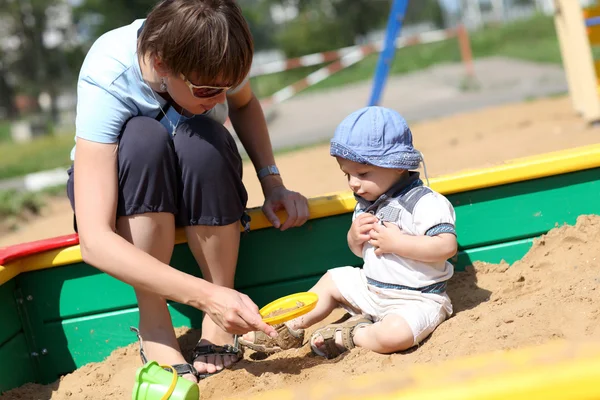 Criança e sua mãe em sandbox — Fotografia de Stock