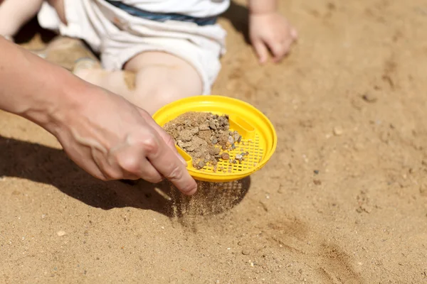 Siktning sand i sandlådan — Stockfoto