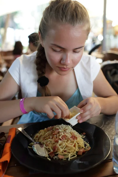 Menina polvilha espaguete com queijo — Fotografia de Stock