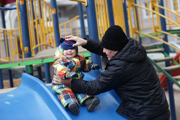 Grandfather holding toddler on slide — Stock Photo, Image