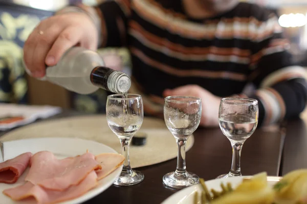 Homme remplissant des verres de vodka — Photo